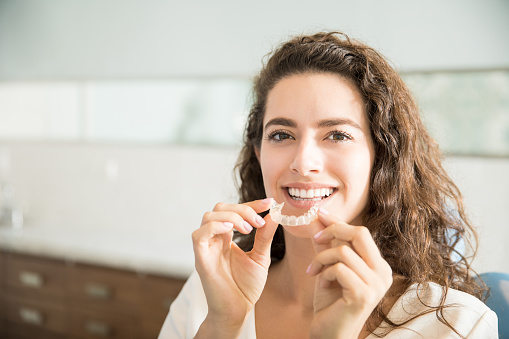 Woman holding a clear aligner at Highridge Dental Care in Folsom, CA