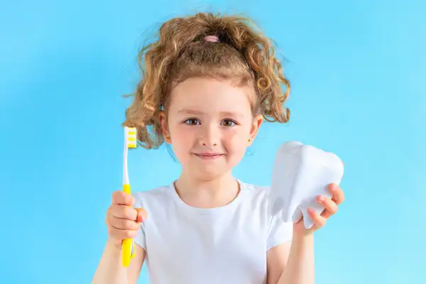 A young girl smiling and holding a toothbrush