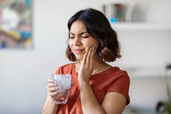 Young woman rubbing her jaw and wincing in pain before emergency treatment